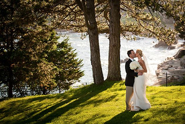 a married couple kissing on the banks of a river